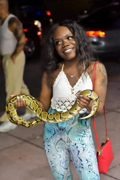 Woman smiling holding a python at night