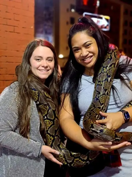 Two women posing with a large snake in Miami