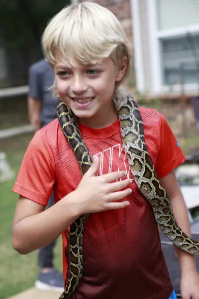 Boy with a snake around his neck at a party