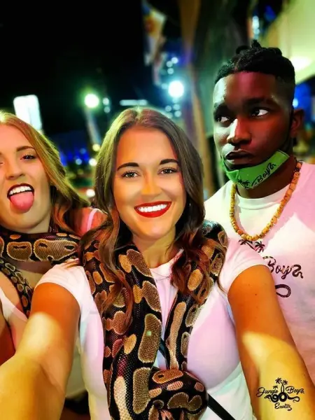 Three people taking a selfie with a snake