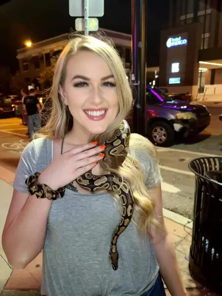 Smiling woman with a snake around her neck at night