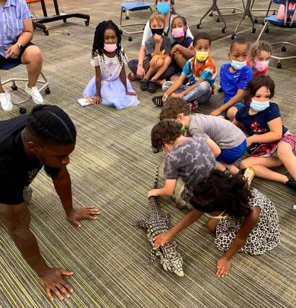 Children interacting with an Argentinian Tegu named Zork